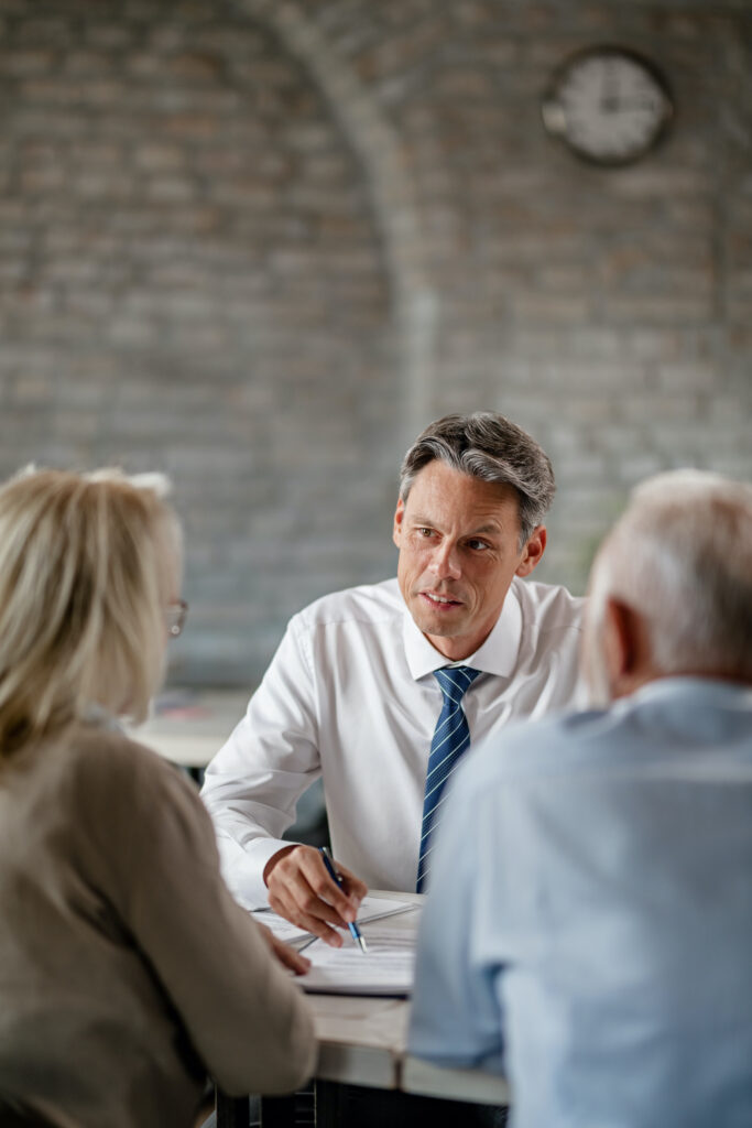 Insurance agent and mature couple communicating while analyzing loan documents in the office.