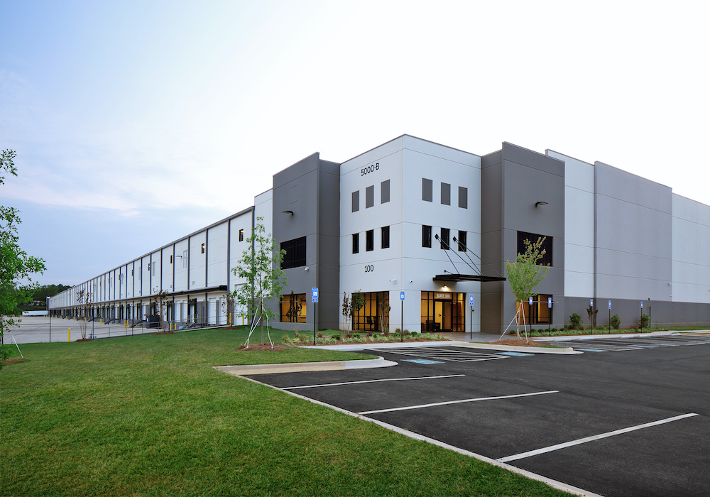 Modern gray industrial warehouse distribution building and parking lot